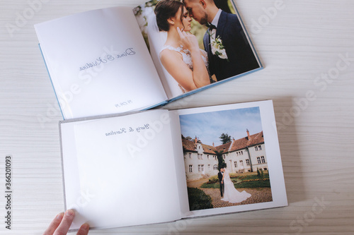 Two open photobook with groom and bride on white wooden table. Comparison