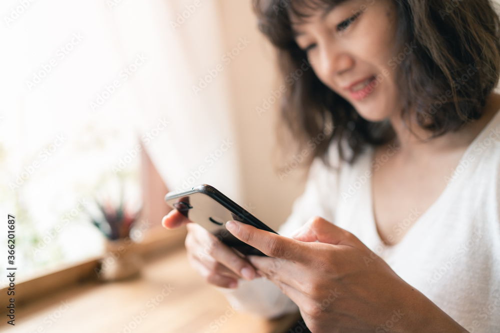 Close up hands of Asian woman using smartphone chatting and searching information with blurry smiley face background. copy space of technology business and social distancing concept Close up hands of Asian woman using smartphone chatting and searching information with blurry smiley face background. copy space of technology business and social distancing concept