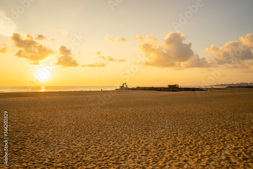 construction activity on the beach during sunrise and a cloudy sky