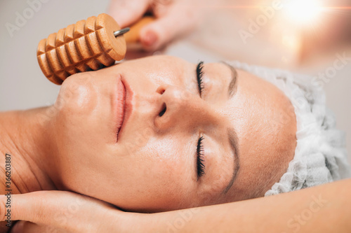 Maderotherapy Face Massage with Wooden Roller. Reducing Wrinkles and Sagging Cheeks photo