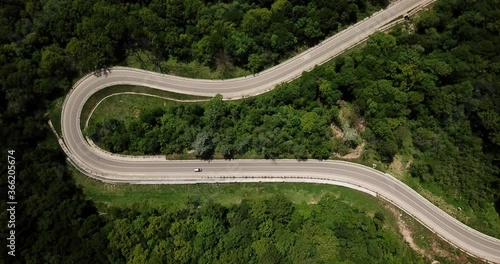 Aerial view from drone of curve road with a car on the mountain with green forest in Russia