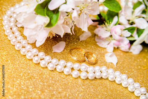 Gold wedding rings and Apple blossoms on a Golden background 