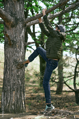 teenage boy poses on a tree, wearing a protective face mask - the concept of modern life and virus protection © soleg