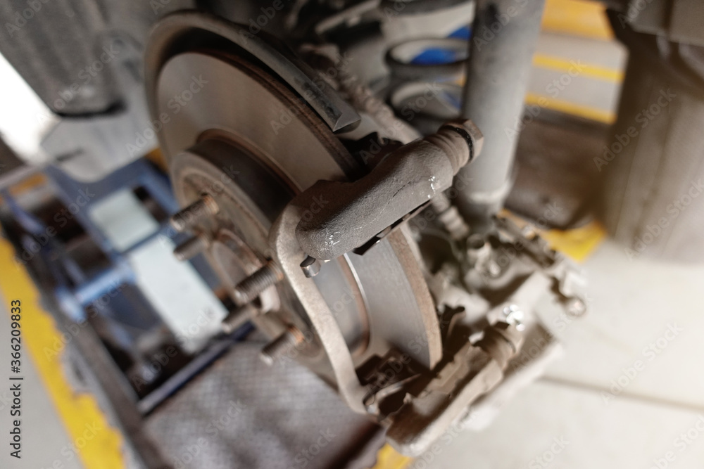 A mechanic repairing, grinding the brake disc and replacing worn out brake pads at an auto
