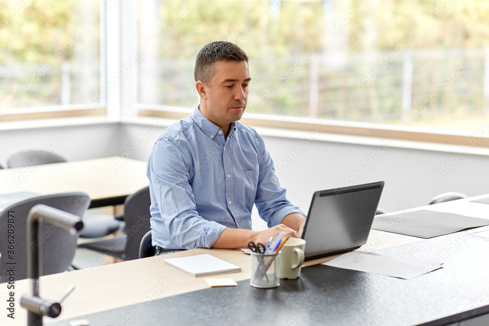 remote job, business and people concept - middle-aged man with laptop computer working at home office remote job, business and people concept - middle-aged man with laptop computer working at home office