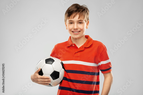 sport, football and leisure games concept - happy smiling boy holding soccer ball over grey background © Syda Productions