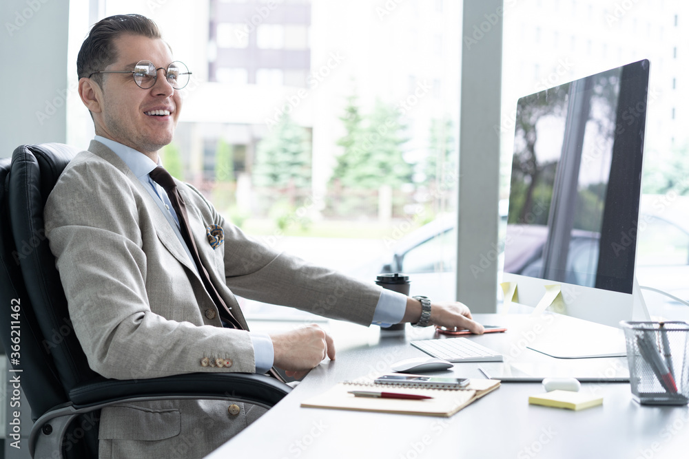 Young employee looking at computer monitor during working day in office Young employee looking at computer monitor during working day in office