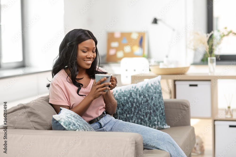people and leisure concept - happy smiling african american woman drinking tea or coffee at home people and leisure concept - happy smiling african american woman drinking tea or coffee at home