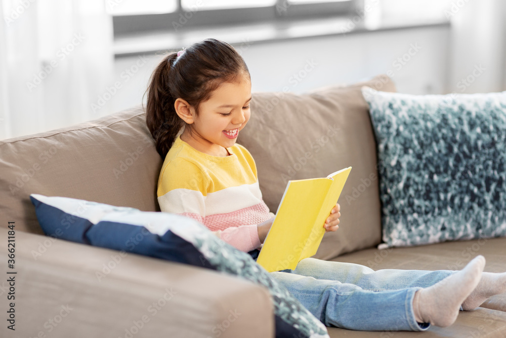 childhood and leisure concept - happy smiling little girl reading book at home childhood and leisure concept - happy smiling little girl reading book at home