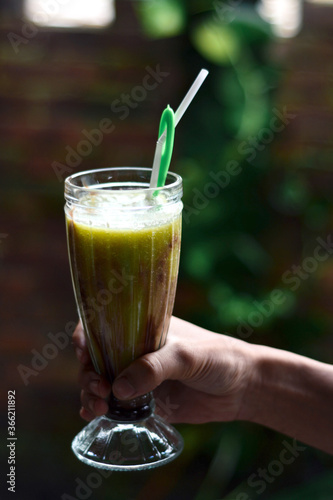 Hands holding fresh avocado juice in a glass