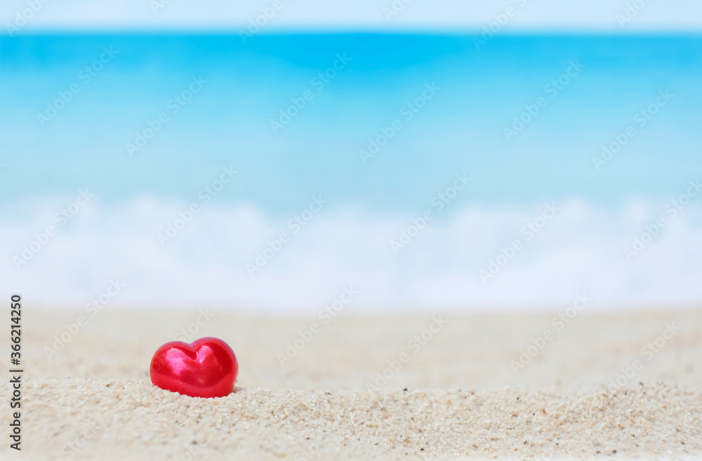 Single red heart on white sand beach with blurred blue sea Single red heart on white sand beach with blurred blue sea
