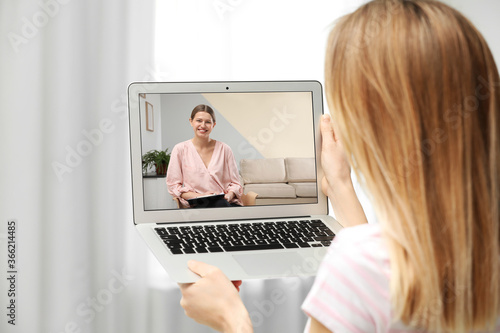 Woman using laptop at home for online consultation with psychologist via video chat, focus on screen photo