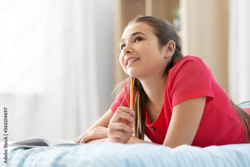 people and leisure concept - happy smiling teenage girl with diary and pencil lying on bed at home people and leisure concept - happy smiling teenage girl with diary and pencil lying on bed at home