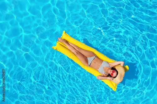 Young woman with inflatable mattress in swimming pool, top view