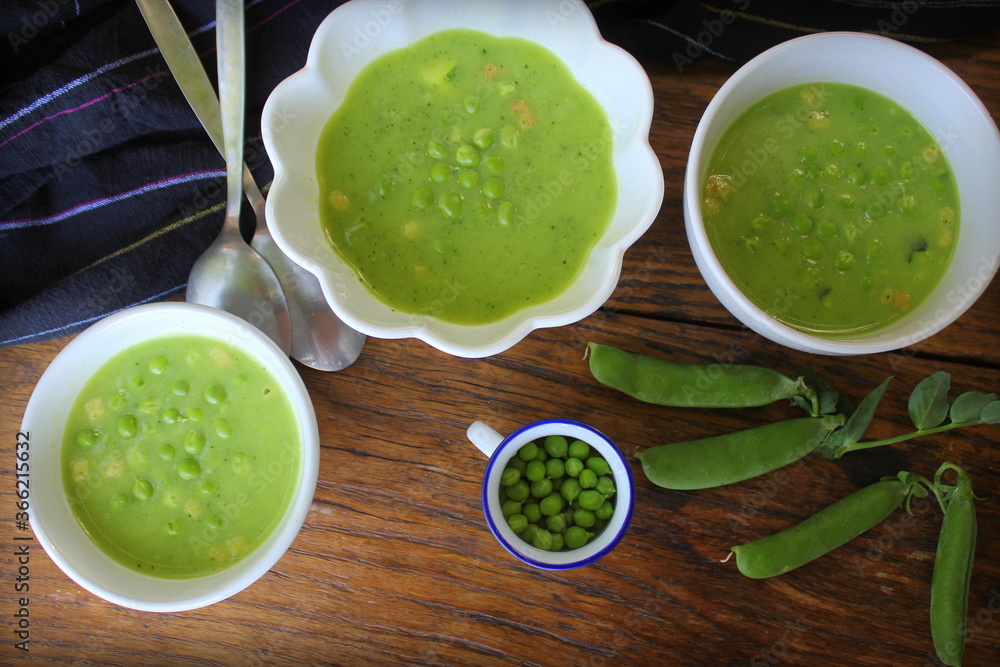 Fresh green pea soup with pea seeds and pea pods around , top view Fresh green pea soup with pea seeds and pea pods around , top view