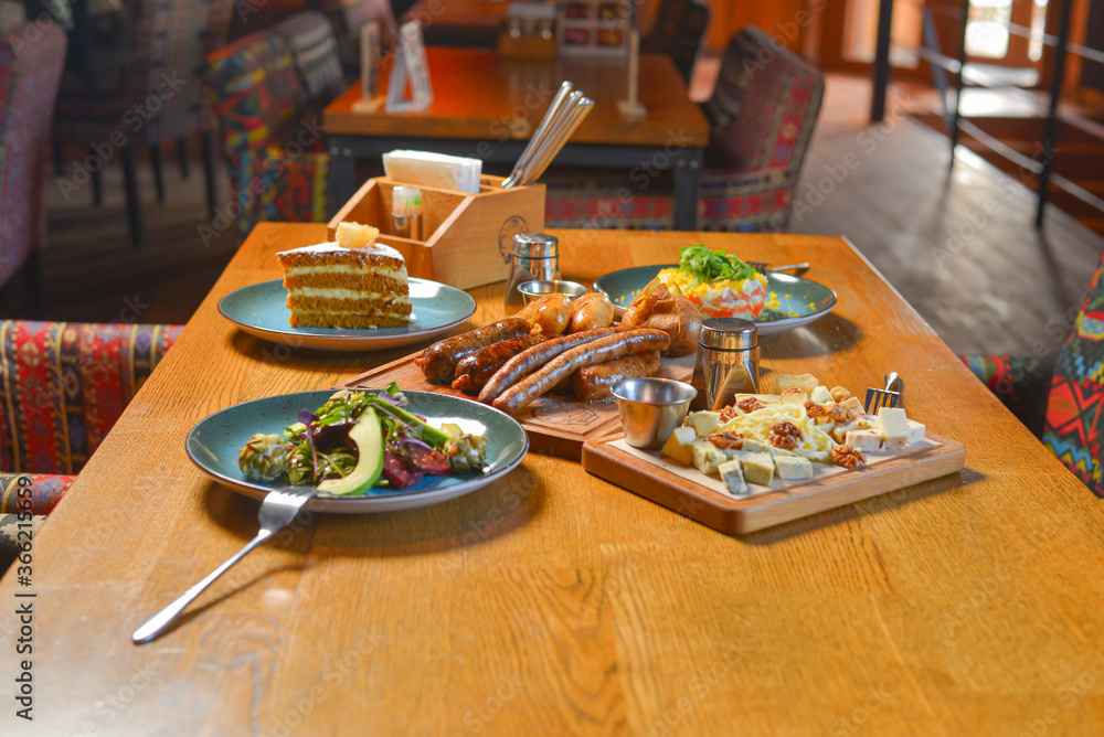 Delicious dinner in restaurant. Served dinner. German Thuringer sausage or bratwurst. Avocado salad with lemon. Delicious dinner in restaurant. Served dinner. German Thuringer sausage or bratwurst. Avocado salad with lemon.