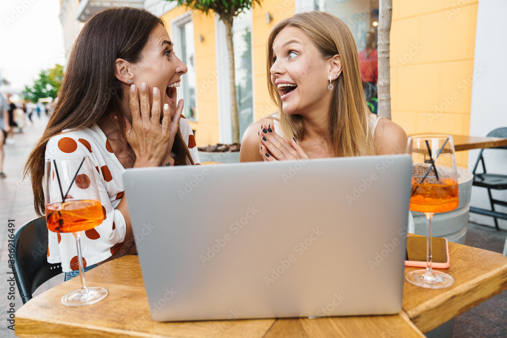 Image of delighted women expressing surprise while using laptop Image of delighted women expressing surprise while using laptop