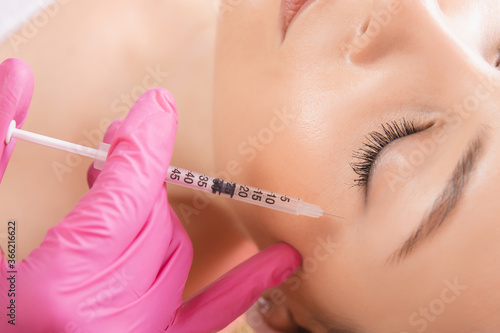 Woman getting injection procedure anti wrinkle corners of eyes forehead face skin. Beauty salon care