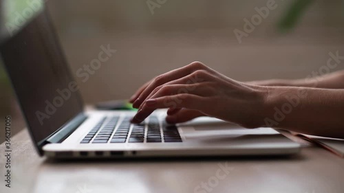 Close-up of hands of unrecognizable business person typing on laptop keyboard at the desk in home office. Closeup of female hands working on laptop keyboard. Businesswoman using modern computer.
