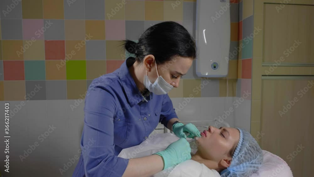 A qualified beautician does a procedure to correct the lips. Lip augmentation with hyaluronic acid in the cosmetology studio. The master performs a procedure of lip correction A qualified beautician does a procedure to correct the lips. Lip augmentation with hyaluronic acid in the cosmetology studio. The master performs a procedure of lip correction