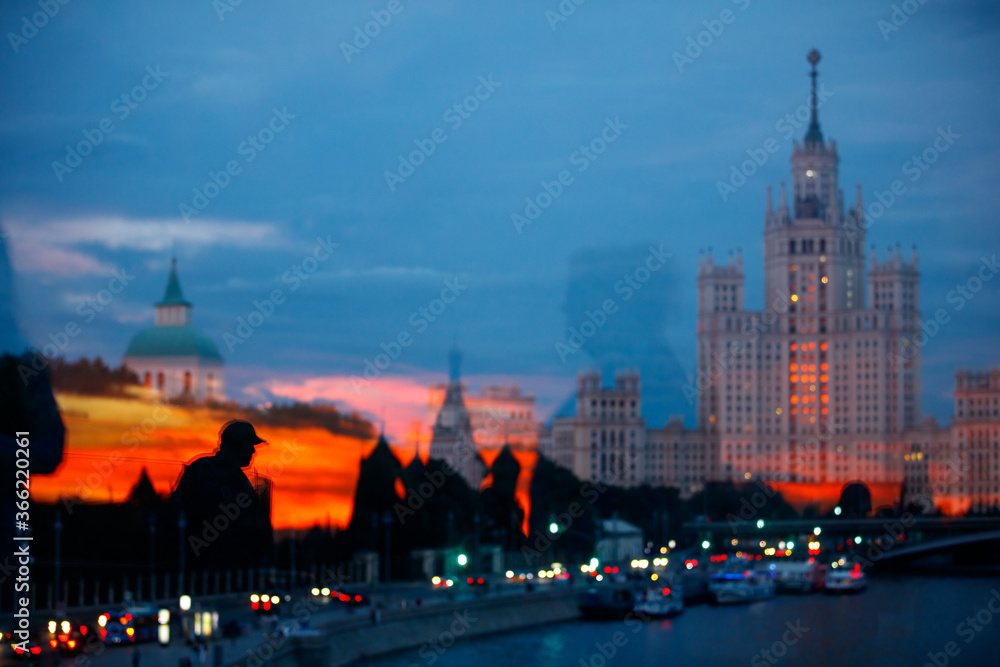 Obraz premium Silhouette of a man in a cap against the background of the evening city