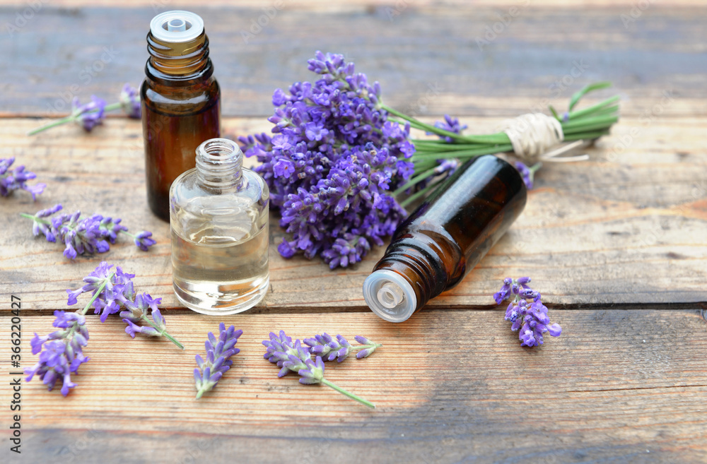bottles of essential oil with one spilled on wooden background and bouquet of lavender flowers bottles of essential oil with one spilled on wooden background and bouquet of lavender flowers