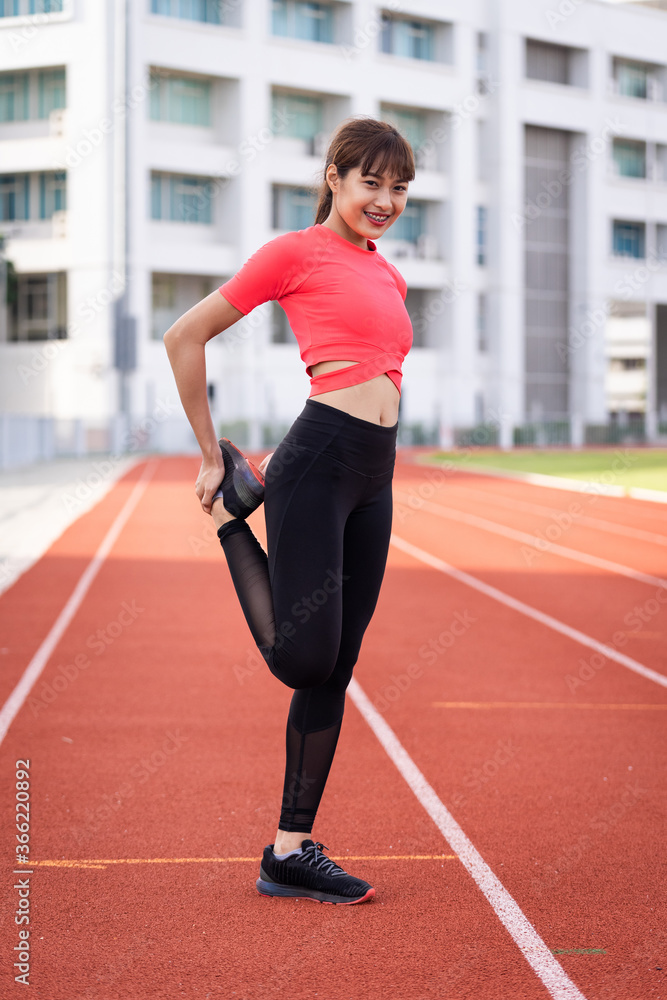 Portrait of a young woman runner warm up and stretching before workout in the morning in city stadium. Healthy and recreation stock photo.