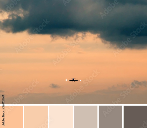 Beautiful dramatic gray and bright orange clouds in the sky  a small silhouette of airplane. Color palette swatches  natural combination of colors.