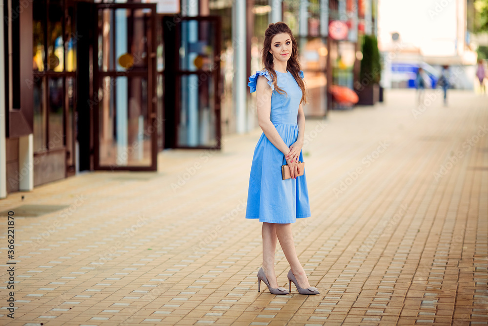 beautiful young woman in a blue dress on a walk on the city street beautiful young woman in a blue dress on a walk on the city street