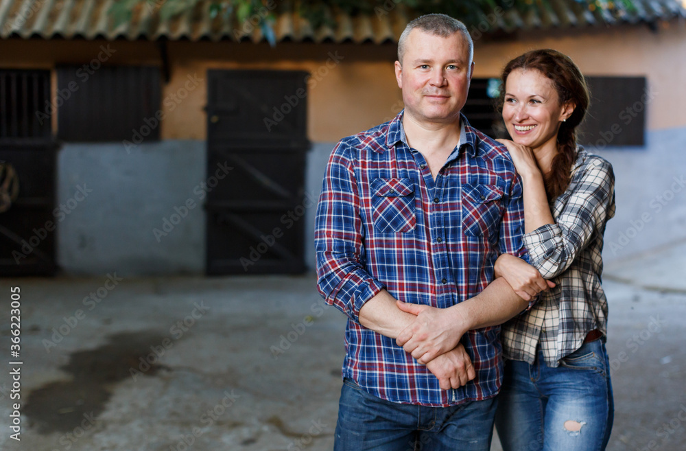 Portrait of smiling couple with girth standing at stable outdoor