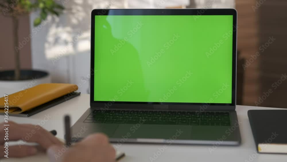 Girl looking at green screen laptop computer in living room watching movie, video content. Indoors. Online education. Business woman or female freelancer working from home office. Closeup 4K Girl looking at green screen laptop computer in living room watching movie, video content. Indoors. Online education. Business woman or female freelancer working from home office. Closeup 4K