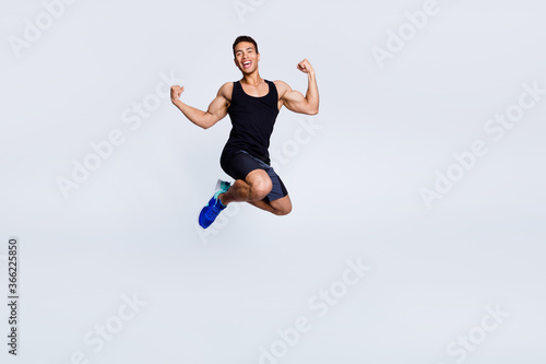 Full length body size view of his he nice attractive sportive muscular cheerful cheery glad guy jumping celebrating having fun isolated over light gray pastel color background
