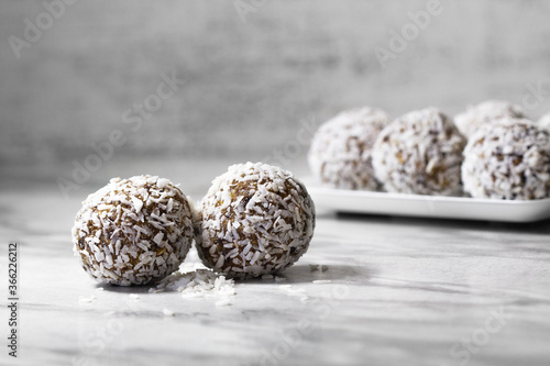 Homemade energy balls with dried apricots, raisins, dates, prunes, walnuts and coconut. Healthy sweet food. Energy balls in a plate on a marble gray background. Close up. Side view. Copy space