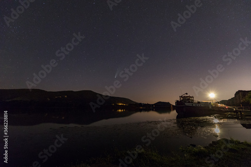 night sky with the comet Neowise above a barge on the Rhone River