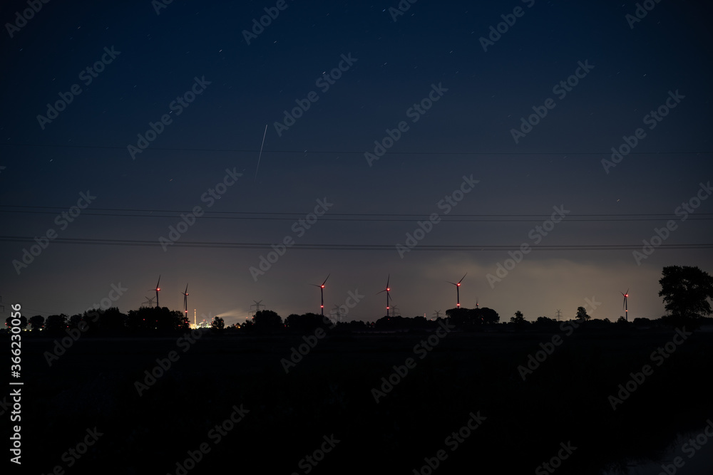 glowing wind turbines with their red lights on the horizon in the dark night