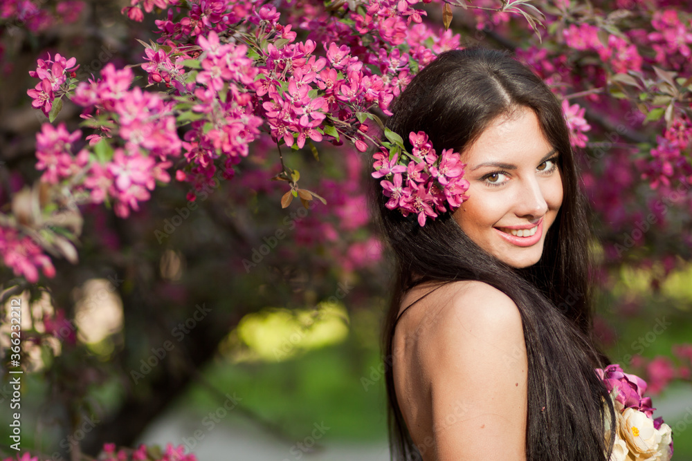 Young woman with pink flowers in hair and onthe background
