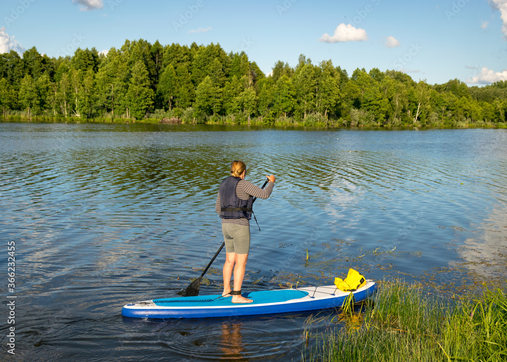 landscape with a woman on a sup board, sunny summer day by the lake, summer