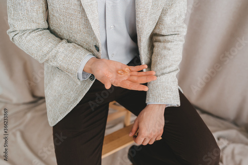 The groom holds a wedding ring in his hand.