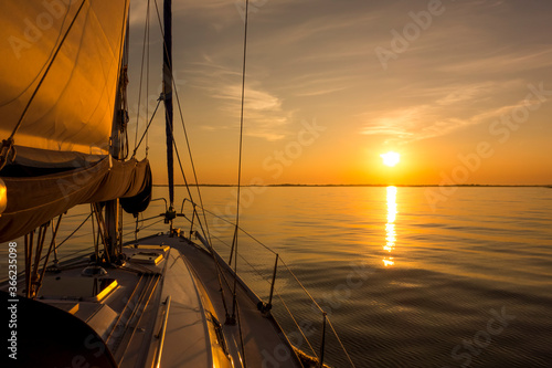 Sailing into the sunset. Yacht with sails and sunset