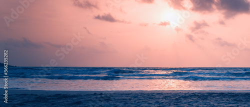 Dawn on the ocean. Sea with waves  sandy beach. Image with retro toning. Beautiful landscape. Banner panorama format