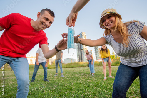 a young woman with a straw hat, and a young man, playing capture the flag in the meadow , whoever wins takes the protective mask, field games, new normal and new sociality
