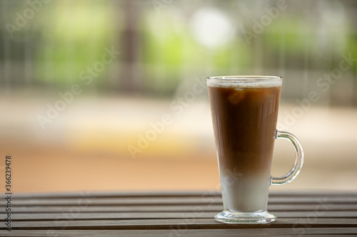 Closeup one glass with ice latte on wooden table. Selective focus