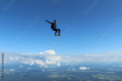 Skydiving. A skydiver is flying above white clouds.