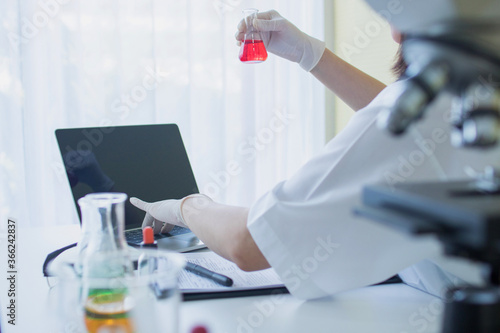 Laboratory Scientists in a Coverall Conducting Research. Chemist or doctor research and test Antiretroviral drugs and find information on laptop , how to resolve coronavirus or covid 19