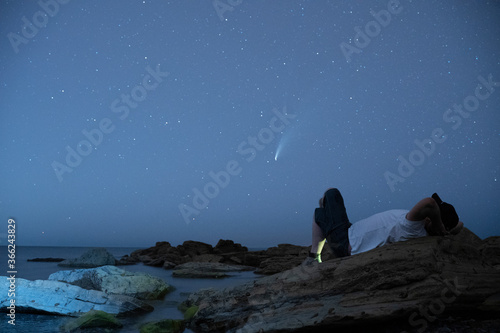 man lieing down looking at neowise comet at night photo