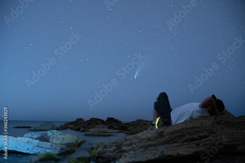 Canvas Print man lieing down looking at neowise comet at night