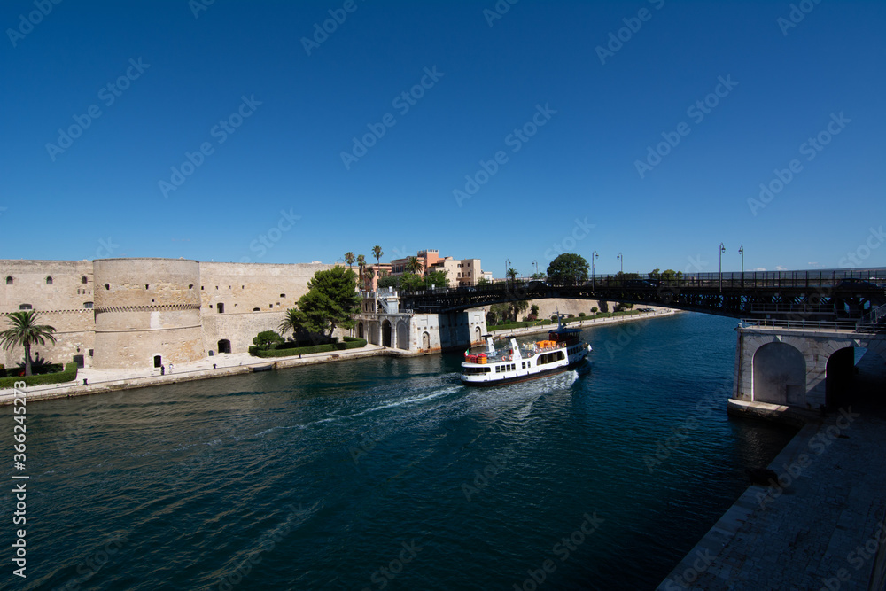 small boat that cross the swing bridge in front of the aragonian castle in taranto on blue sky background