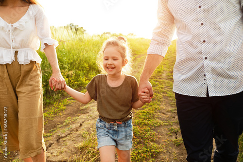 Happy parents and girl walking together in summer outside