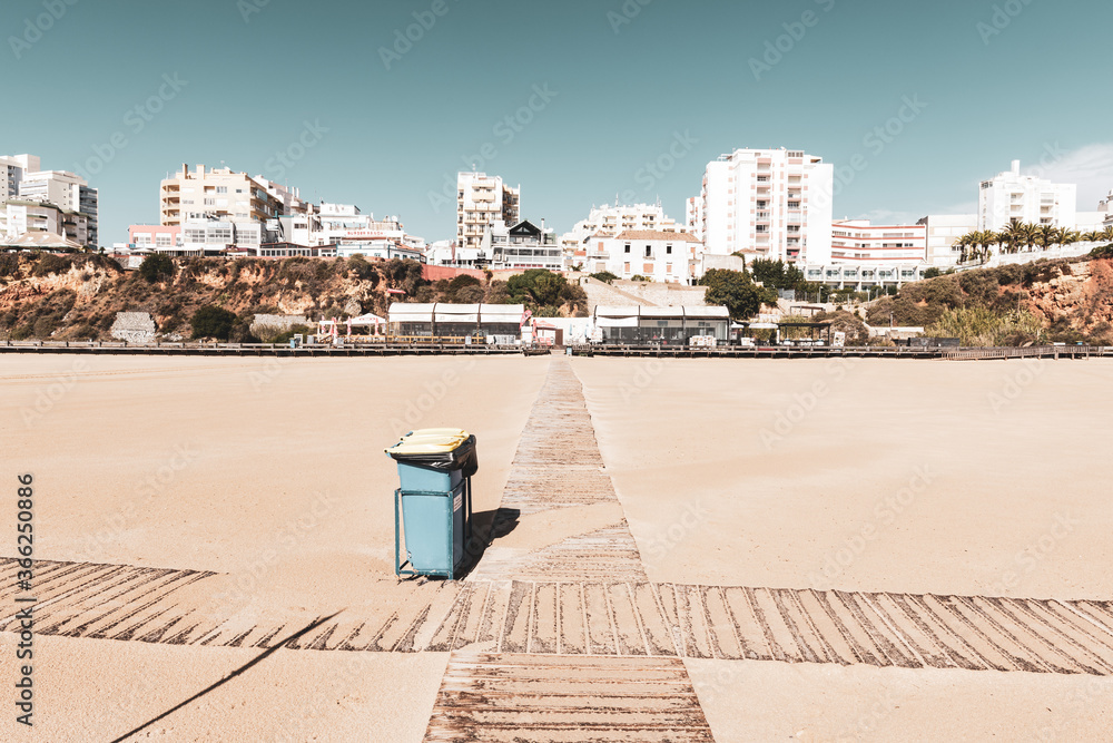 Garbage cans on empty beach in front of city