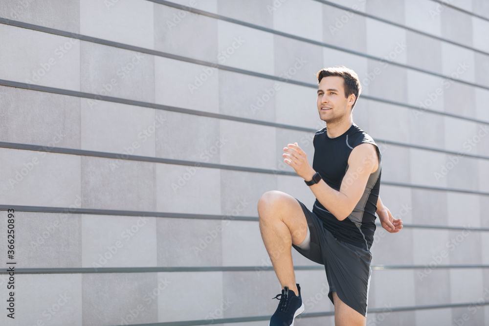 Fototapeta premium Urban style. Man with fitness tracker goes in for sports on gray wall background